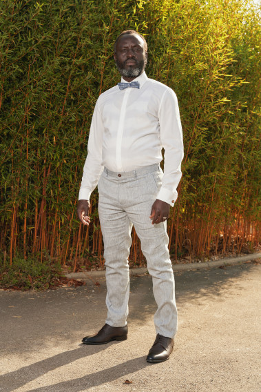 Homme de face en costume GIORGIO couleur bleu clair 3 pièces dans une cours. Zoom sur la chemise blanche.