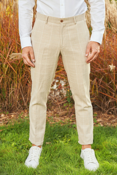 Zoom sur le pantalon GIORGIOC couleur beige à carreaux. Le mannequin porte des baskets blanches.