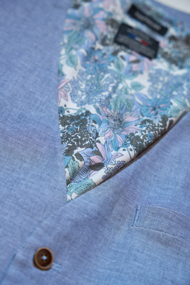 Zoom sur le gilet  LYMAW bleu. Il comporte 6 boutons. L'intérieur comporte des motifs.