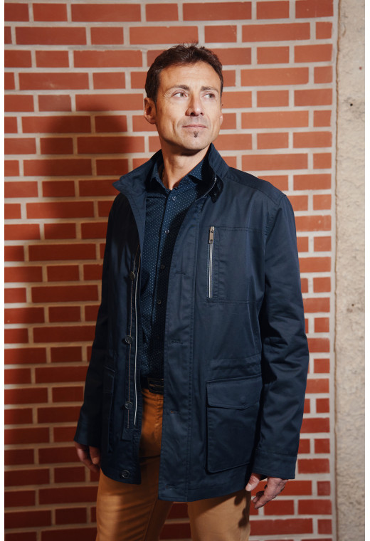 Homme portant la Parka ANNA marine. Elle comporte une poche poitrine, 2 poches plaquées avec rabat.