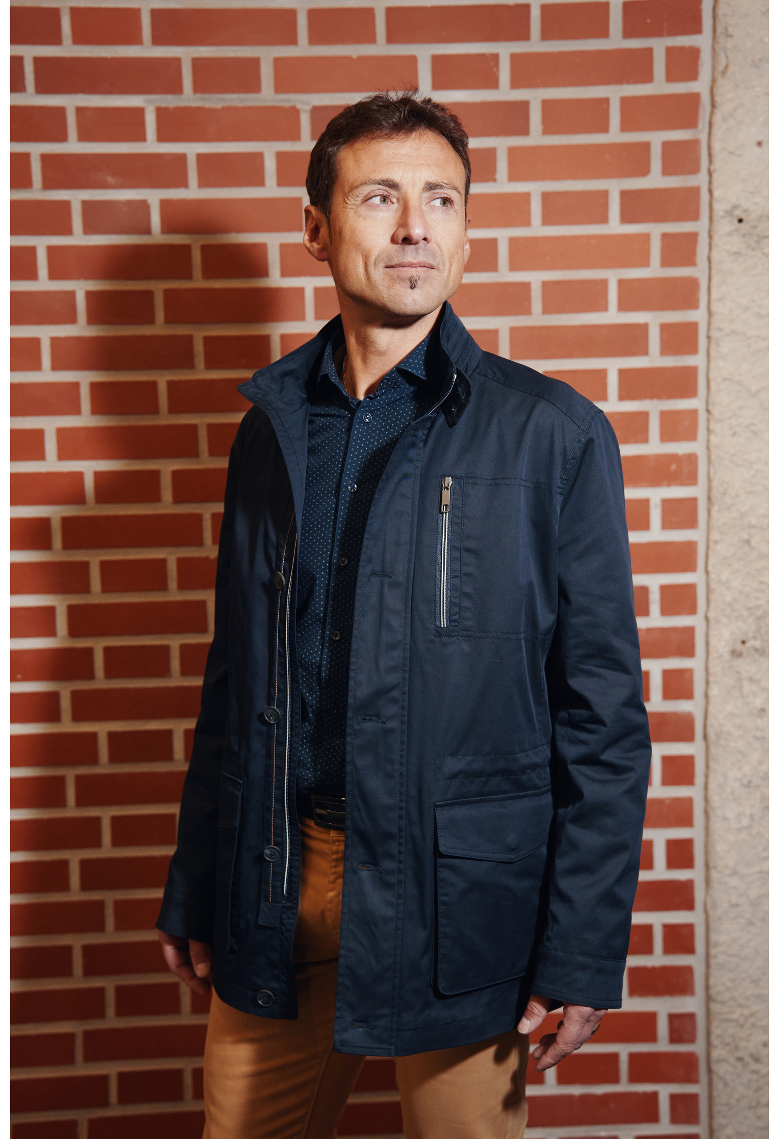 Homme portant la Parka ANNA marine. Elle comporte une poche poitrine, 2 poches plaquées avec rabat.