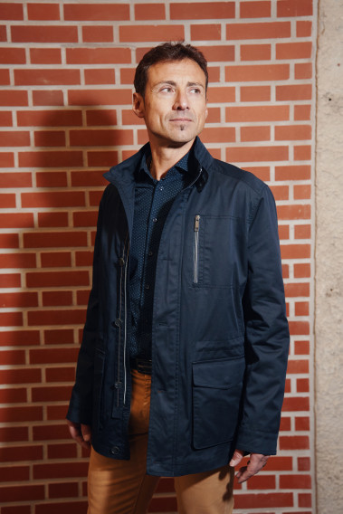 Homme portant la Parka ANNA marine. Elle comporte une poche poitrine, 2 poches plaquées avec rabat.