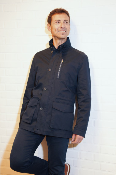 Homme portant la Parka ANNA marine. Elle comporte une poche poitrine, 2 poches plaquées avec rabat.