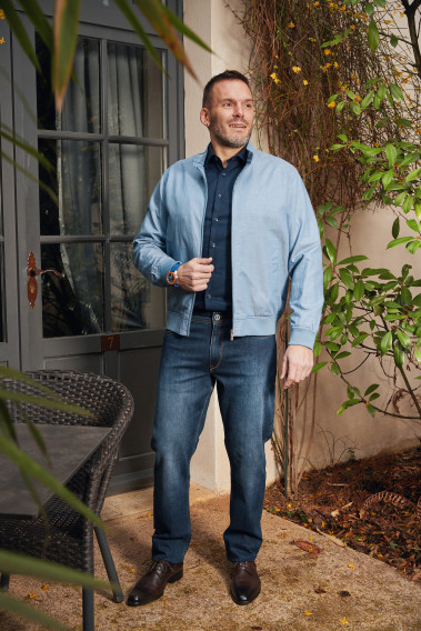 Homme portant le blouson lin HANOT bleu clair. Il comporte 2 poches cotés repose mains.