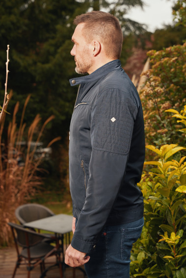 Homme de profil portant le blouson LARIA marine. Il comporte 2 poches poitrine et et 2 poches repose mains.