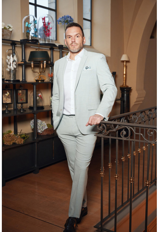 Homme de face en costume OLIVER couleur vert lagon 3 pièces dans une maison.