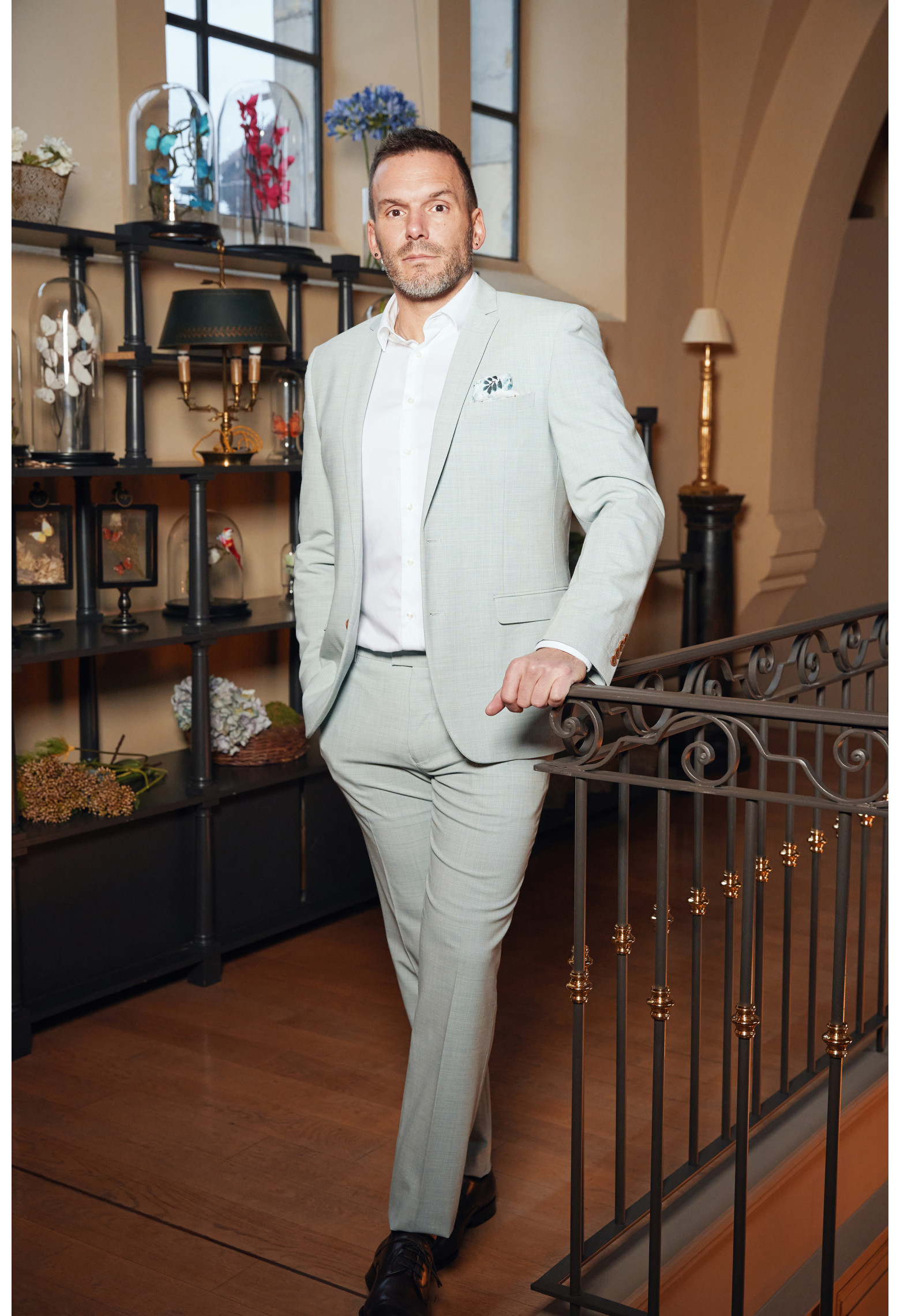 Homme de face en costume OLIVER couleur vert lagon 3 pièces dans une maison.