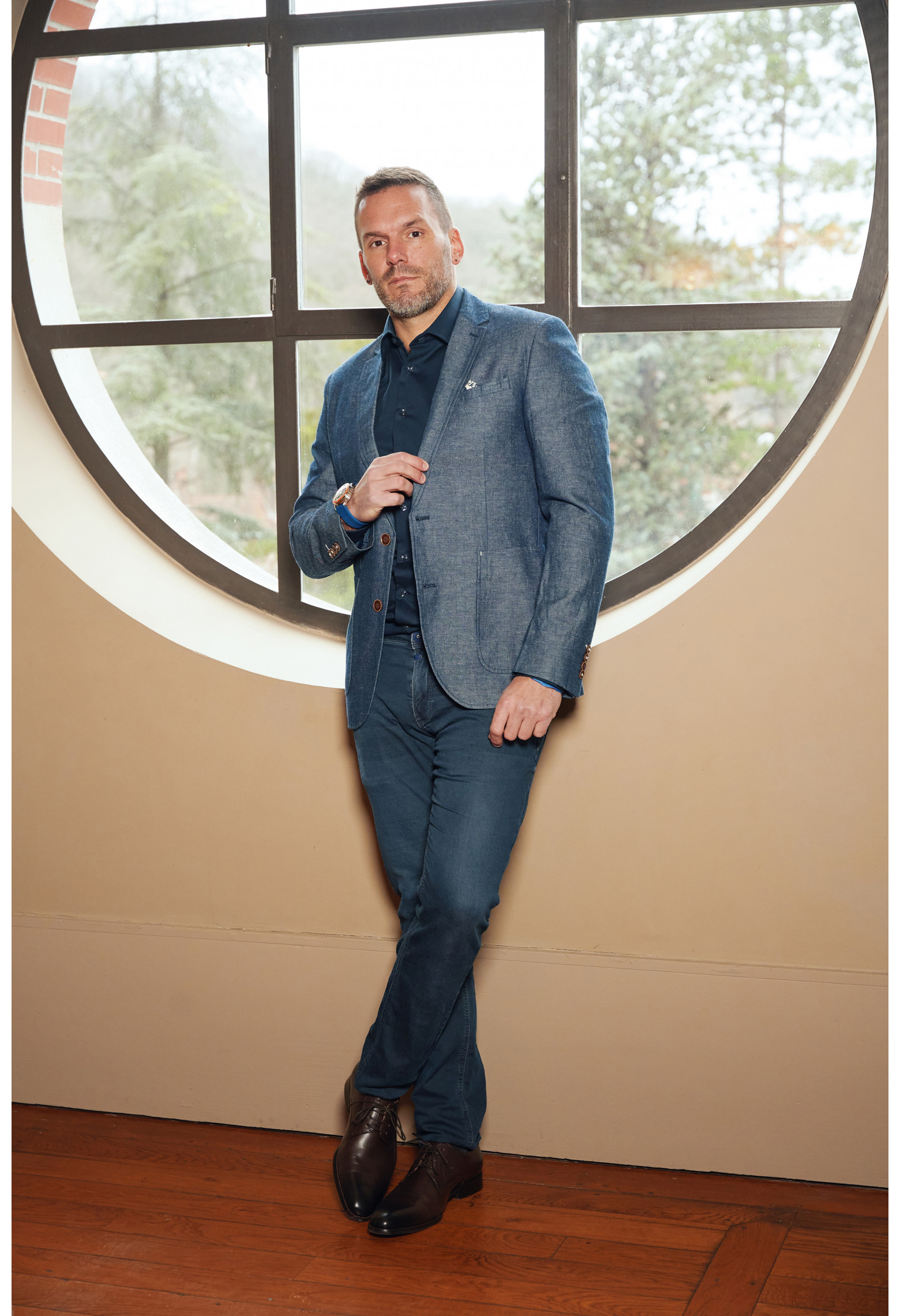 Homme portant la veste OLIVIA bleue. Elle comporte une poches poitrine et 2 poches plaquées.