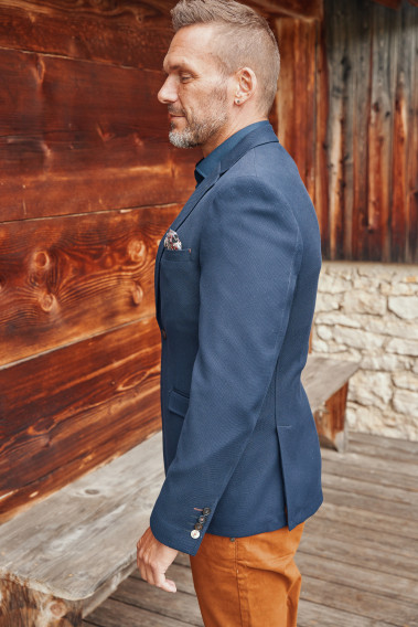 Homme de profil portant la veste TRAVEL marine. Elle comporte une poches poitrine.