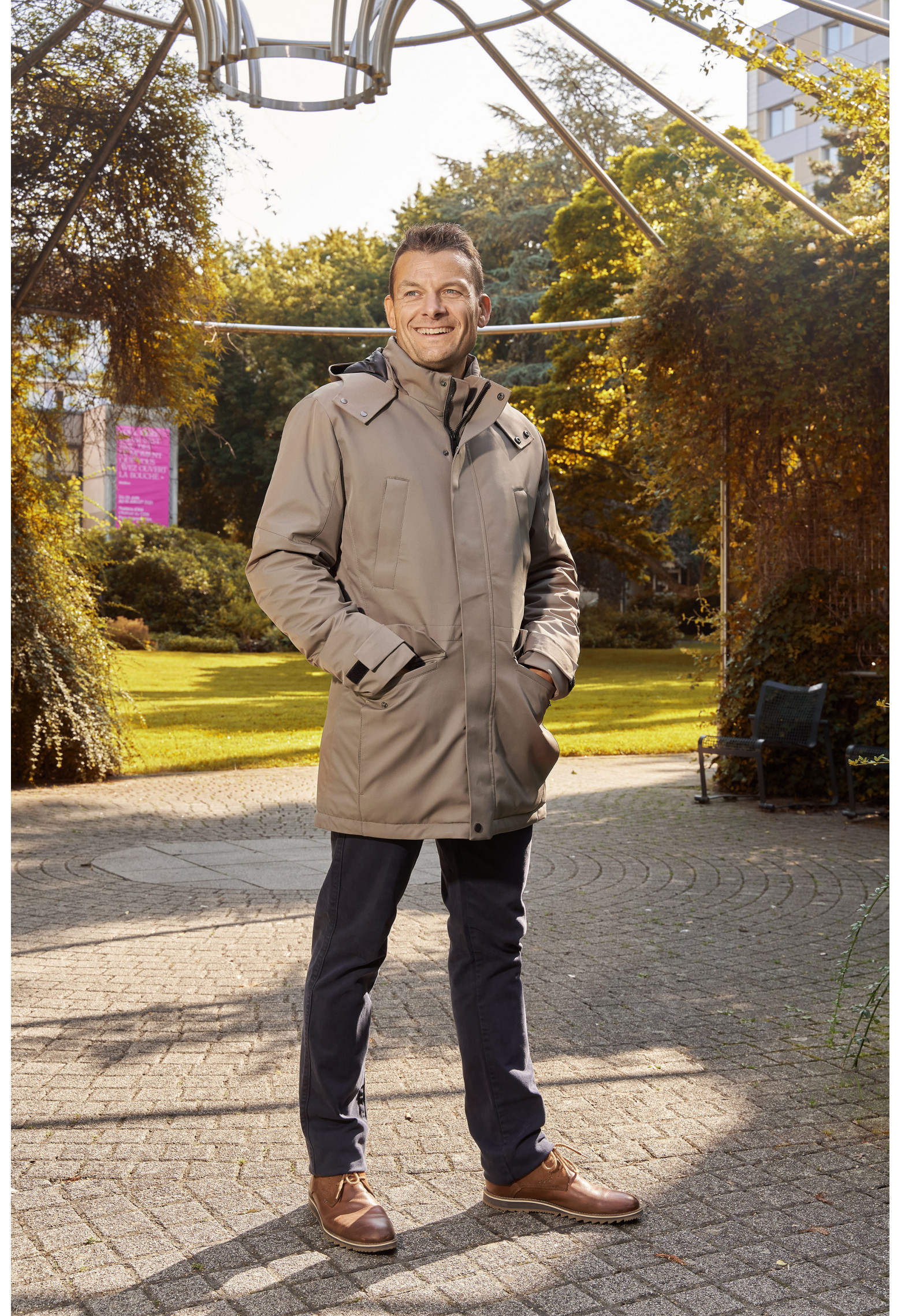 Homme portant la parka SIERA beige. Elle comporte 4 poches et un lien de serrage à la taille.