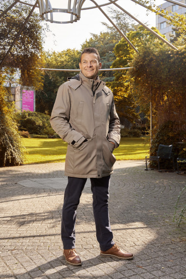 Homme portant la parka SIERA beige. Elle comporte 4 poches et un lien de serrage à la taille.