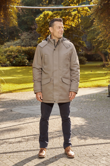 Homme portant la parka SIERA beige. Elle comporte 4 poches et un lien de serrage à la taille.