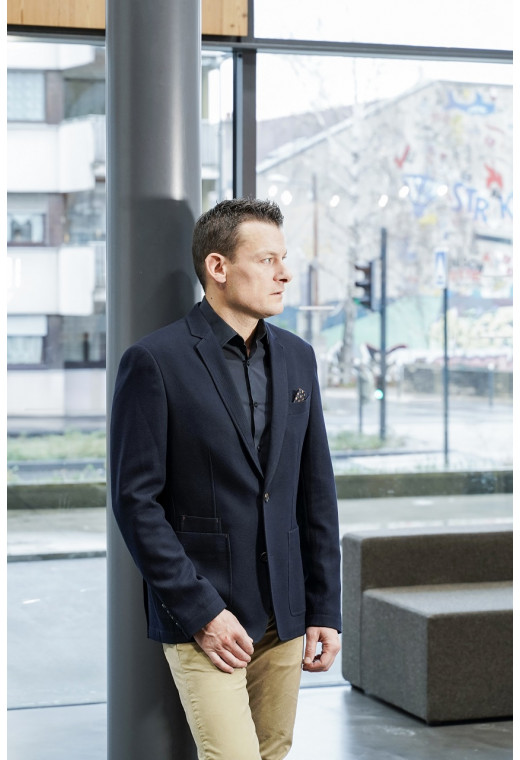 Homme portant la veste slim effet maille marine. Elle comporte une poche poitrine et 2 poches plaquées.