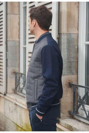 Homme de profil portant le blouson  LEVY bi-matière gris et marine. Il comporte 2 poches repose mains