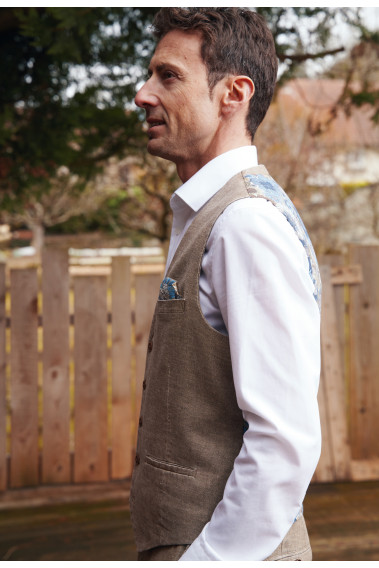 Homme de profil portant le gilet  LYMA sable accompagné d'une chemise blanche et d'un mouchoir de poche.