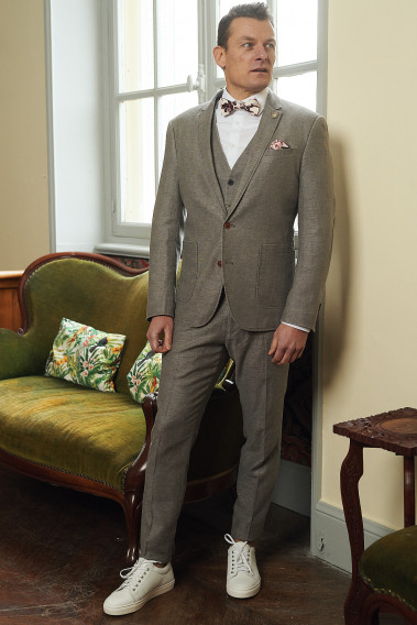 Homme portant la veste SAFARY taupe. Elle comporte une poche poitrine et 2 poches  plaquées.