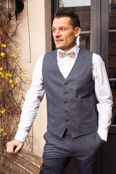 Homme portant le gilet  LYMAW bleu accompagné  d'un nœuds papillon.