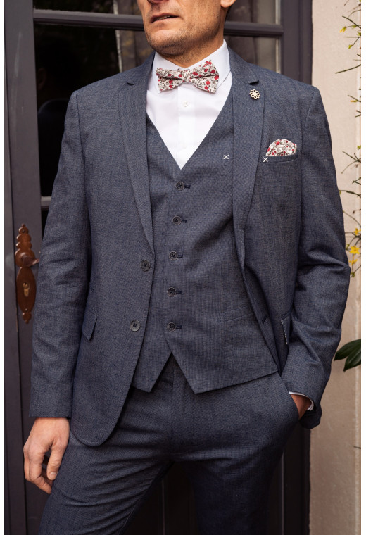 Homme portant le gilet  LYMAW bleu accompagné de sa veste et d'un nœuds papillon.