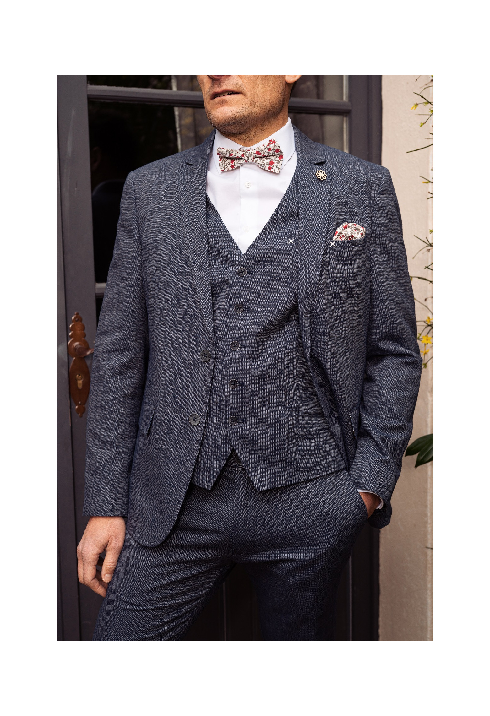 Homme portant le gilet  LYMAW bleu accompagné de sa veste et d'un nœuds papillon.