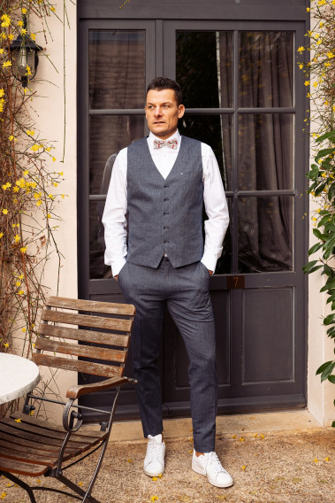 Homme portant le gilet  LYMAW bleu accompagné  d'un nœuds papillon.