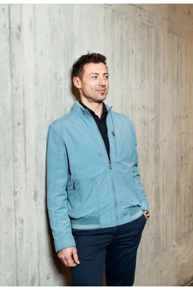 Homme portant le blouson  CLYDE bleu clair. Il comporte une poche poitrine et  2 poches repose mains.