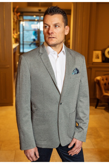 Homme portant la veste JEFF grise. Elle comporte une poche poitrine et 2 poches plaquées.