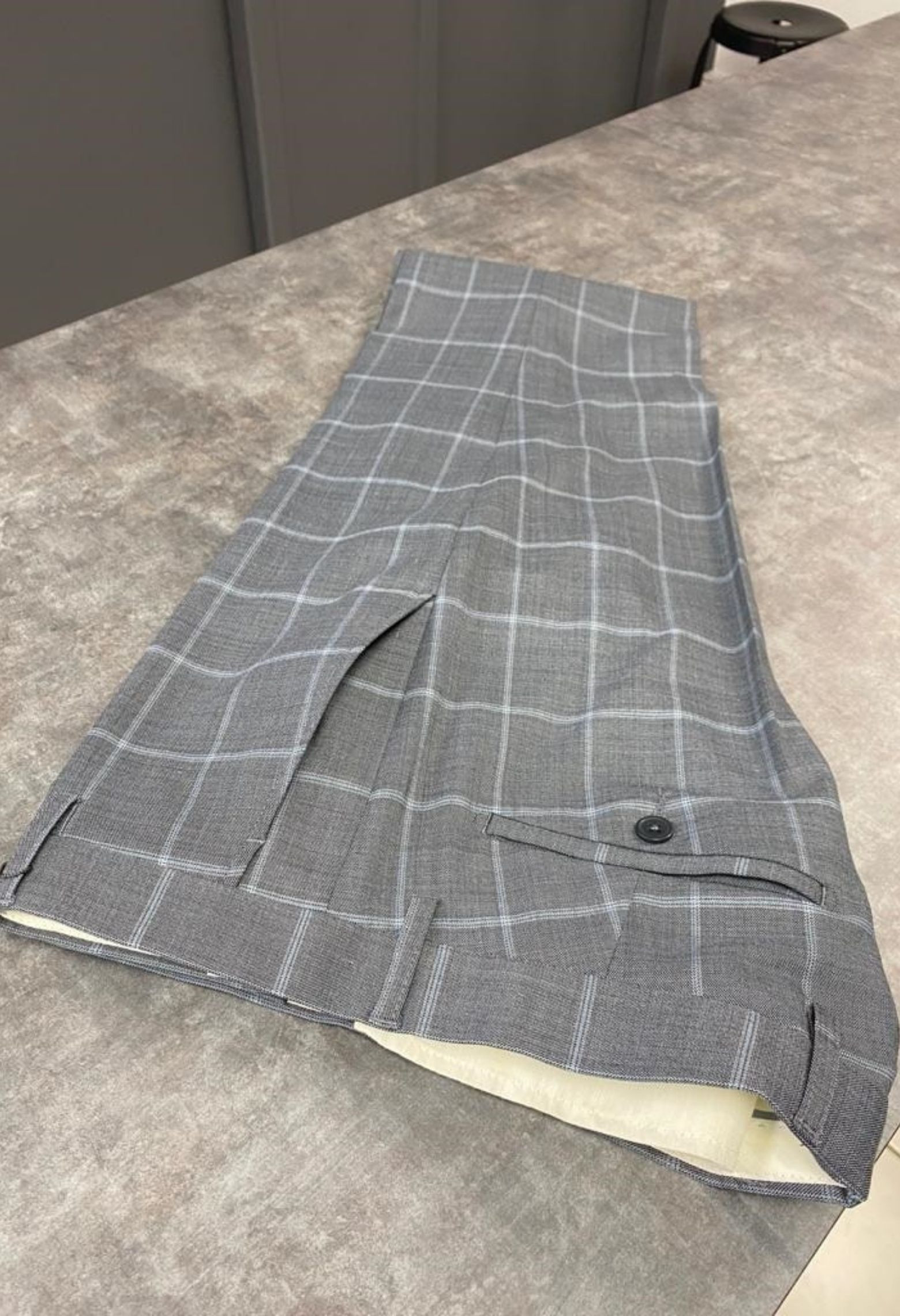 Homme portant le pantalon SULTAN à carreaux gris. Il comporte 2 poches avant et 2 poches arrière.