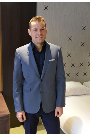 Homme portant la veste SULTAN gris bleuté. Elle comporte une poche poitrine et 2 poches rabats