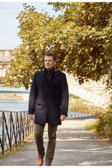Homme portant le manteau AZARIA marine. Il est long et comporte une poche poitrine et 2 poches repose mains.