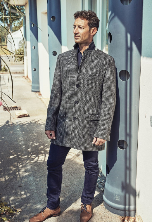 Homme portant le manteau SUAVE noir et gris. Il est long et comporte 3 poches.