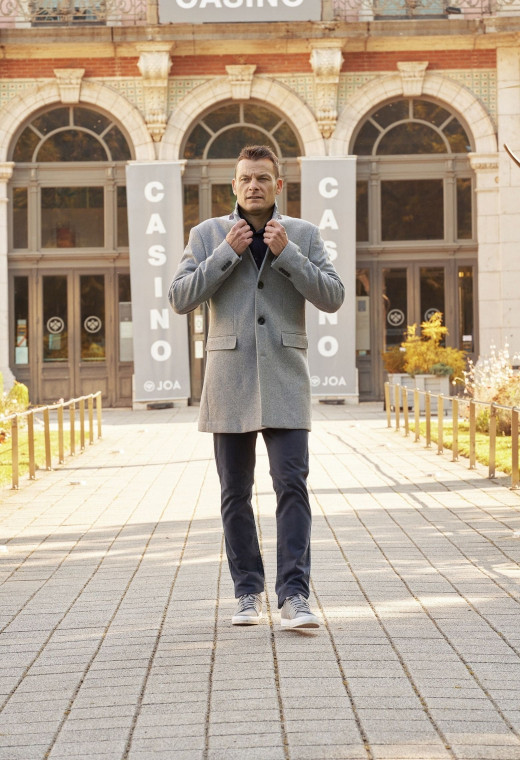 Homme portant le manteau SUAVE gris clair. Il est long et comporte 3 poches.