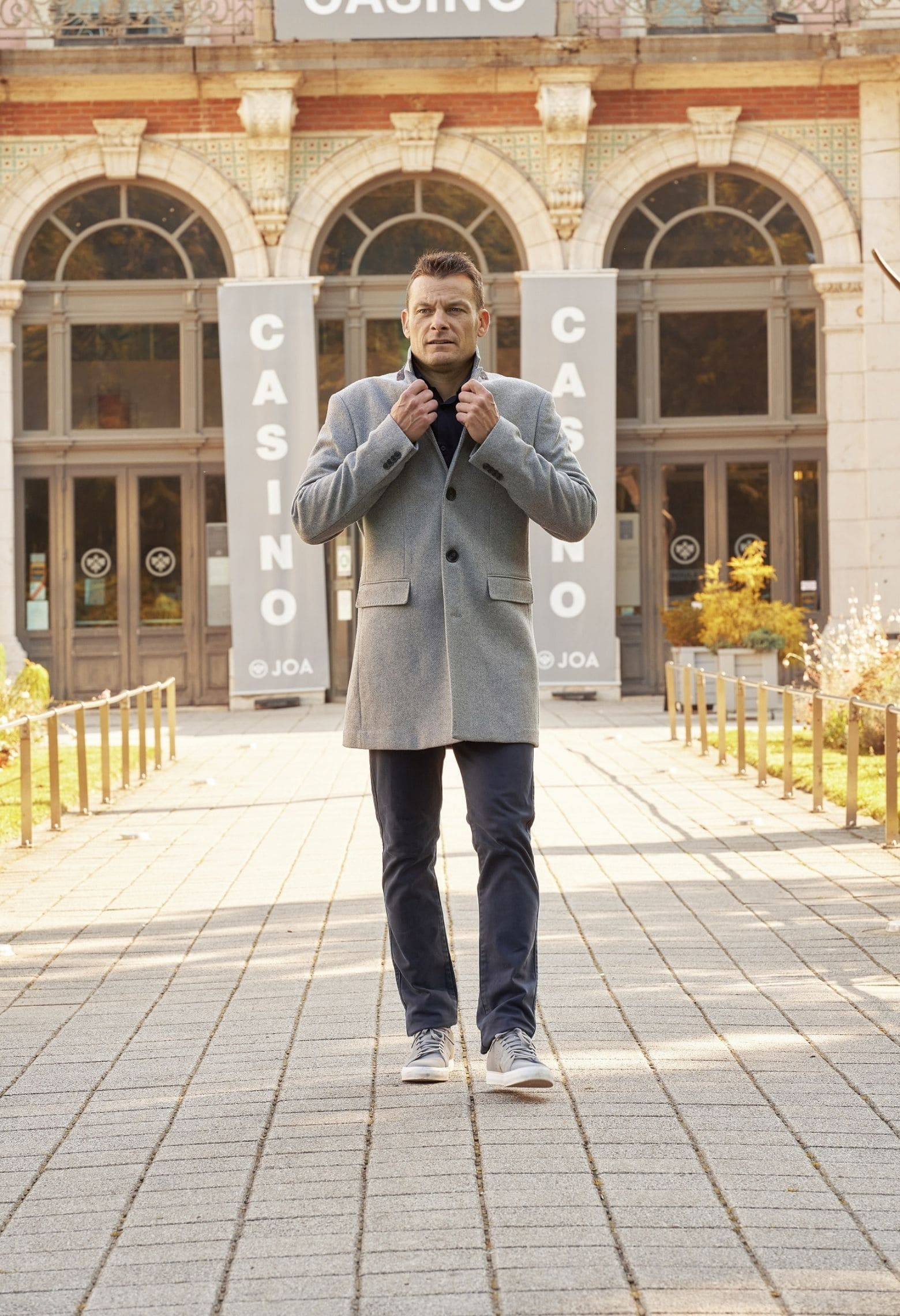 Homme portant le manteau SUAVE gris clair. Il est long et comporte 3 poches.