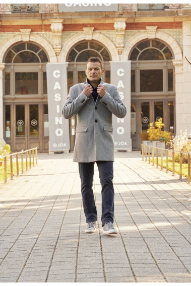 Homme portant le manteau SUAVE gris clair. Il est long et comporte 3 poches.