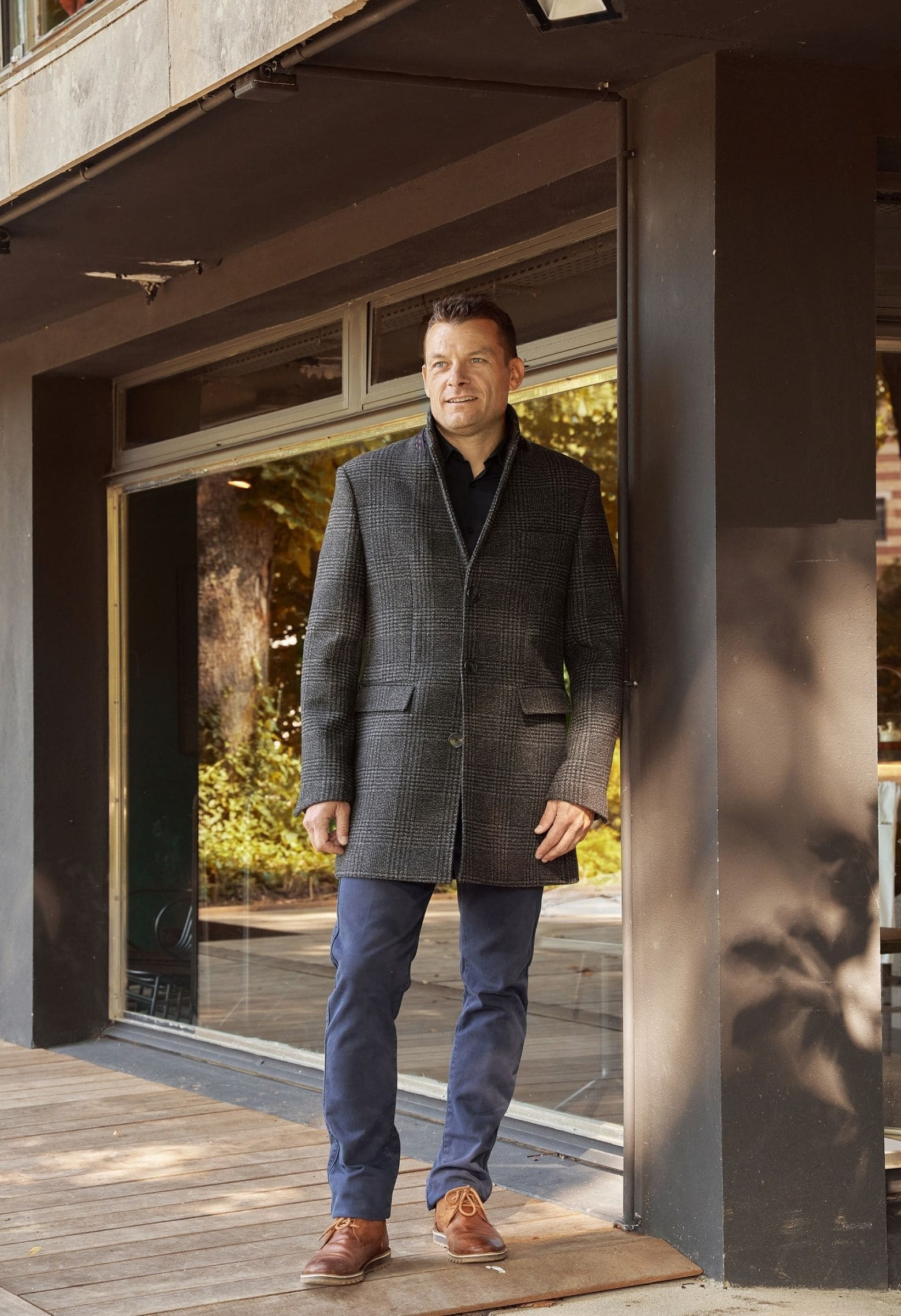 Homme portant le manteau SUAVE gris foncé. Il est long et comporte 3 poches.