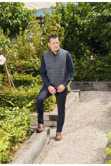 Homme portant la doudoune sans manche KOS grise. Elle comporte 2 poches repose mains.