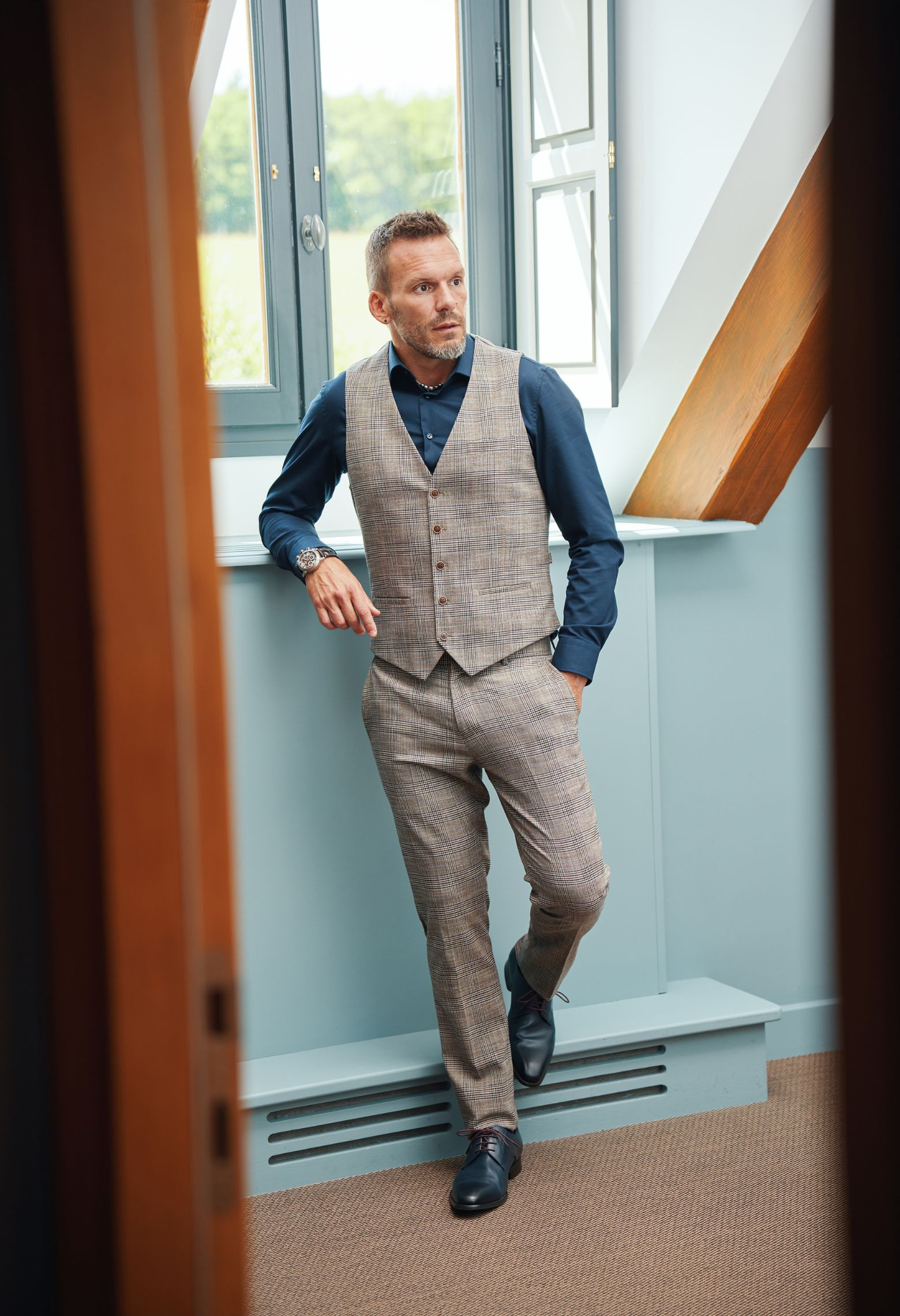 Homme portant le pantalon LINCOLN carreaux marron. Il comporte 3 poches avant et 2 poches arrière.