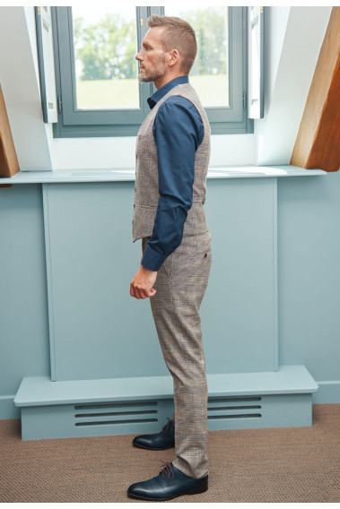 Homme de profil portant le pantalon LINCOLN carreaux marron. Il comporte 3 poches avant et 2 poches arrière.