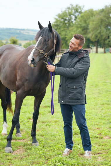 Homme portant la parka OCTAVIA kaki. Elle comporte 4 poches.