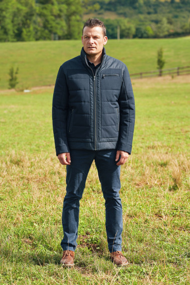 Homme portant le blouson MYKA bleu. Il comporte une poche poitrine et 2 poches verticales.