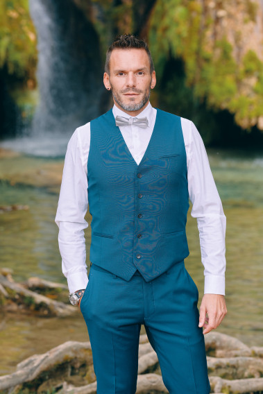 Homme portant le gilet CHRIS bleu-vert accompagné d'un nœuds papillon.