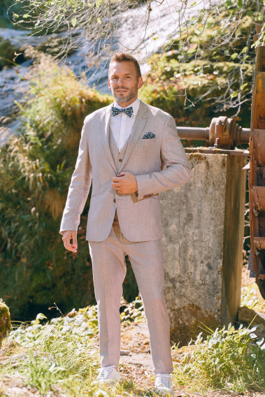 Homme de face en costume GIORGIO couleur rose poudré 3 pièces dans une cours.