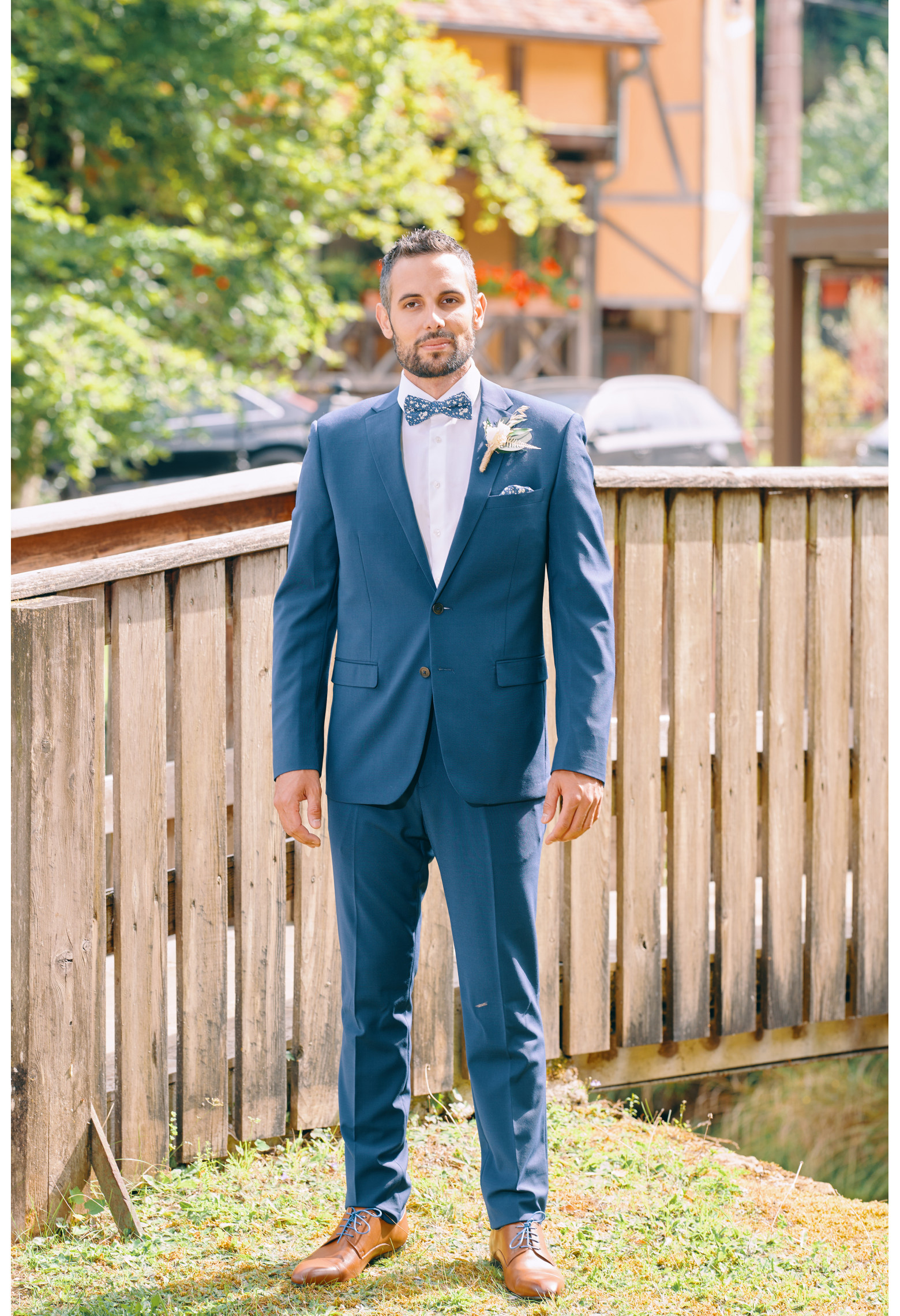Homme de face en costume SUAT couleur bleu 2 pièces sur un balcon.