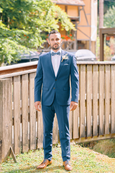 Homme de face en costume SUAT couleur bleu 2 pièces sur un balcon.