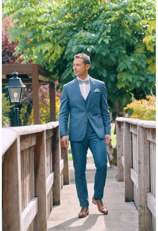 Homme portant la veste TROPICAL bleue. Elle comporte une poche poitrine et 2 poches  plaquées.