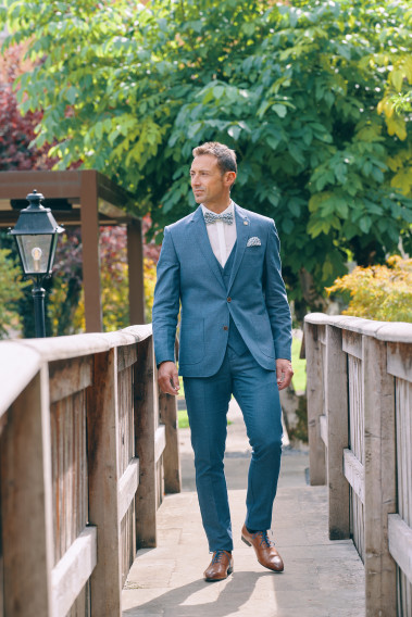 Homme portant la veste TROPICAL bleue. Elle comporte une poche poitrine et 2 poches  plaquées.