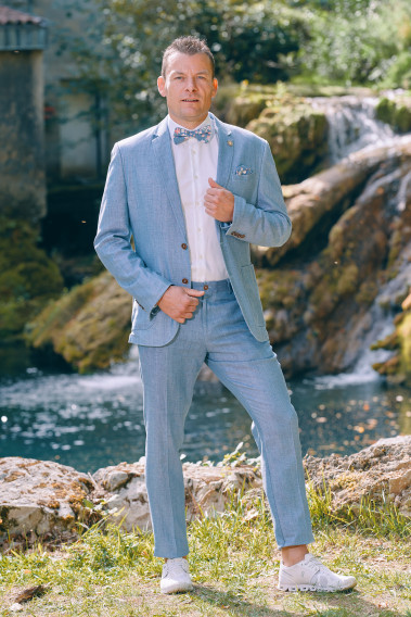 Homme portant la veste TROPICAL bleue. Elle comporte une poche poitrine et 2 poches plaquées.