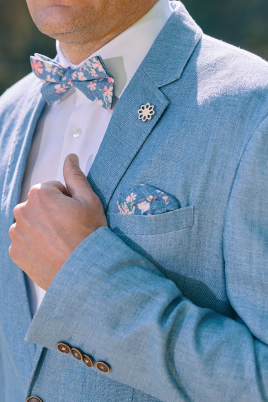 Zoom sur la veste TROPICAL bleue. L'homme porte un nœuds papillon et un mouchoir de poche.