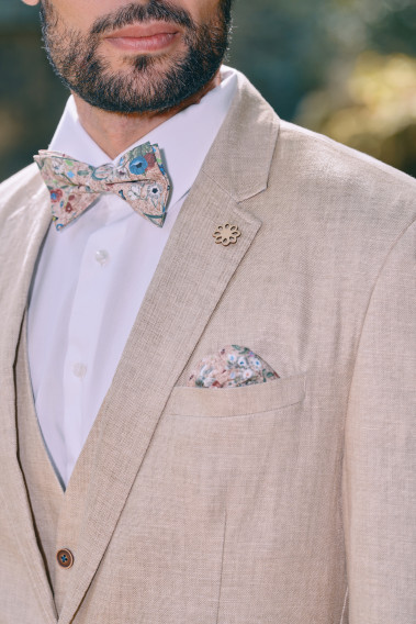 Zoom sur la veste TROPICAL sable. L'homme porte une nœuds papillon et un mouchoir de poche.