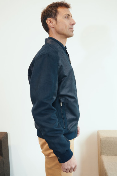 Homme de profil portant le blouson OTHELLO suède marine. Il comporte 2 poches repose mains.