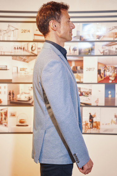 Homme de profil portant la veste VALENTINA bleu clair.